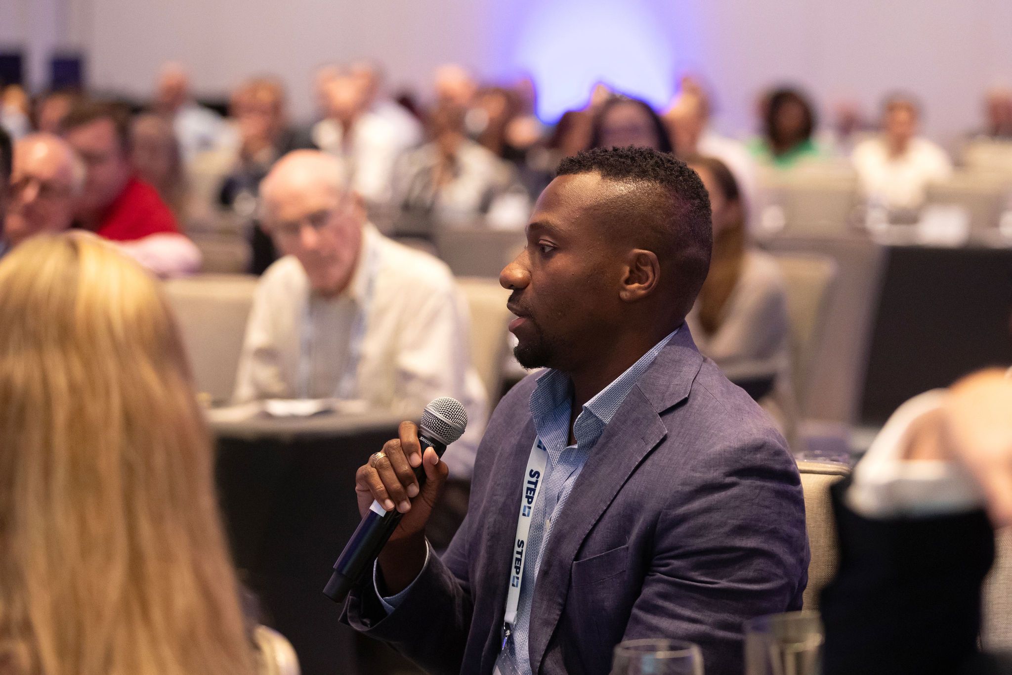 A Black man weaing a blue suit holds a microphone